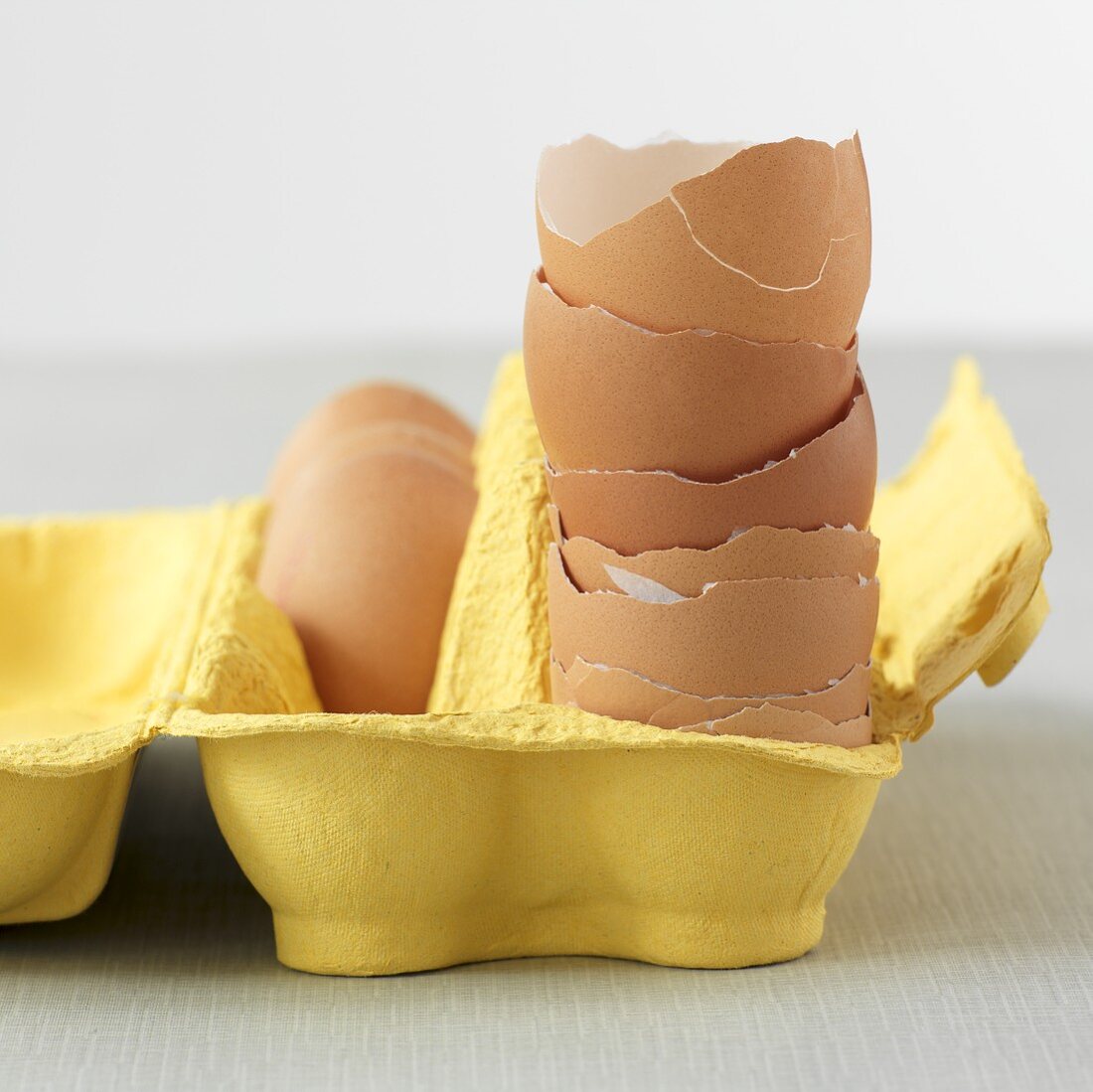 Gestapelte Eierschalen in gelber Eierschachtel