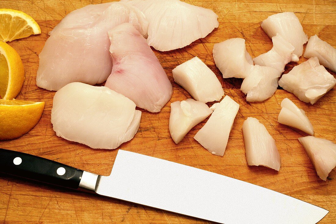 Whole and Cut Fresh Halibut Cheeks; Cutting Board and Knife