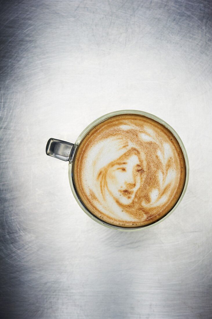 Bild eines Mädchens im Milchschaum eines Cappuccino