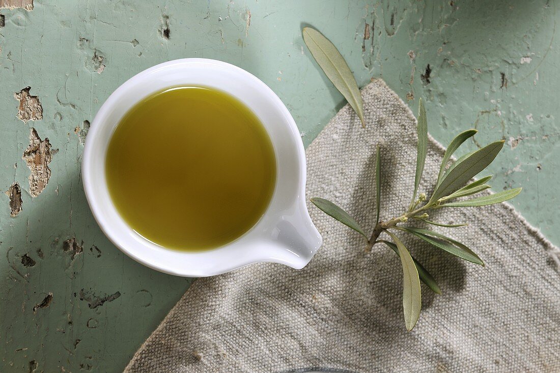 A bowl of olive oil and an olive sprig