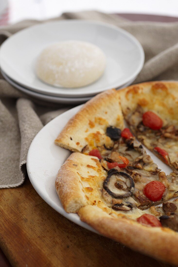 Wild Mushroom and Tomato Pizza; Sliced on a White Plate; Pizza Dough