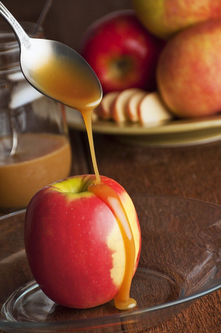 Caramel sauce being poured over an apple