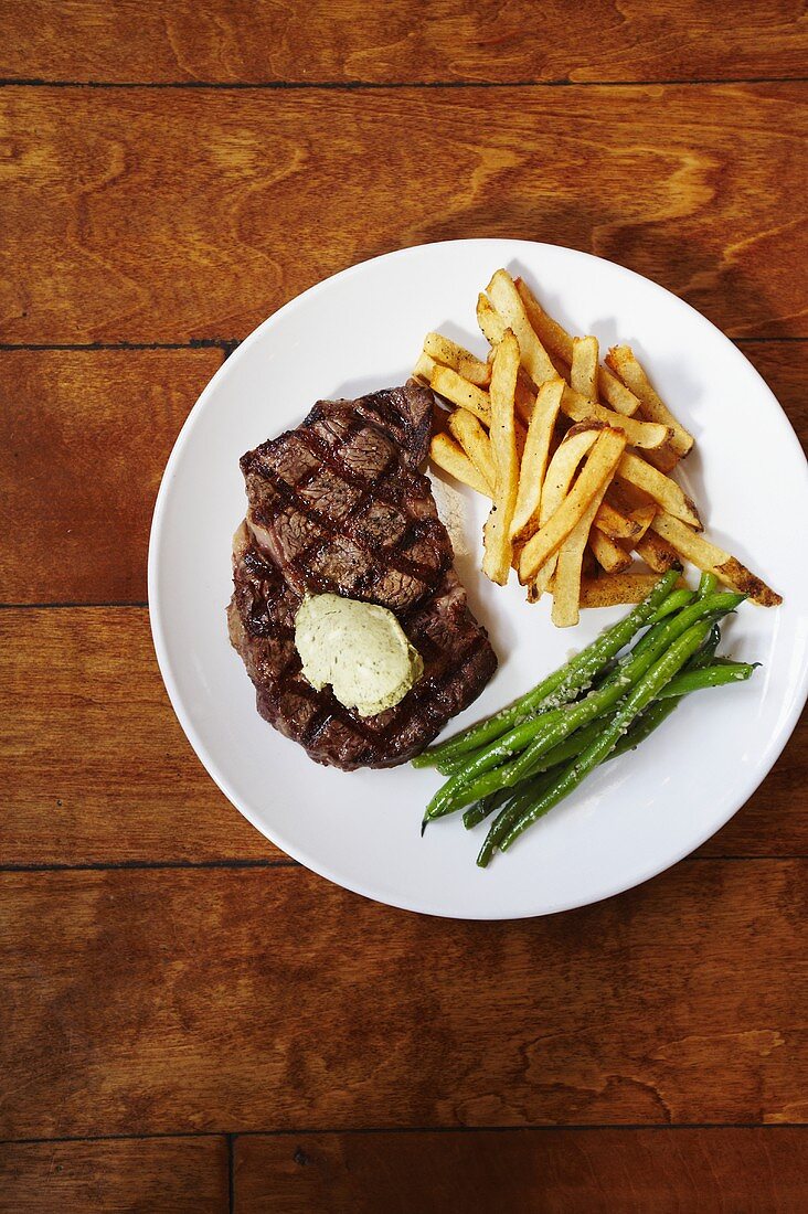 Gegrilltes Steak mit Pommes & grünen Bohnen auf Teller