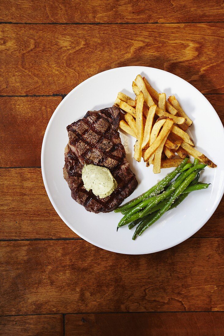 Grilled Steak with French Fries and Green Beans on a White Plate; From Above