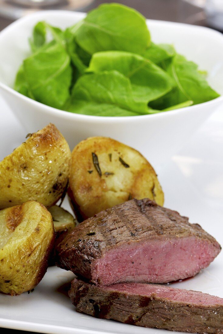 Fried ostrich fillet with spinach salad and rosemary potatoes
