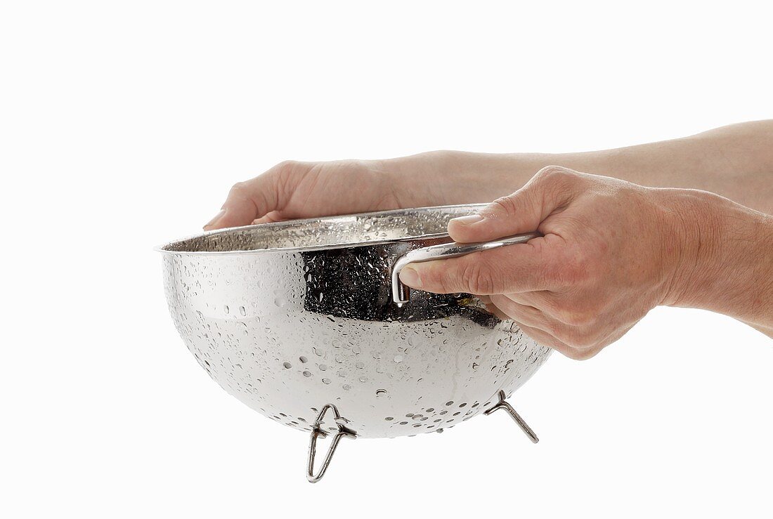 Hands holding a dripping colander