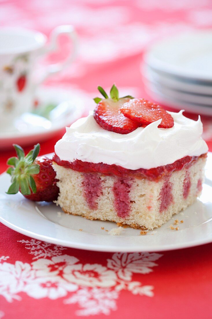 Ein Stück Strawberry Poke Cake mit Schlagsahne (USA)
