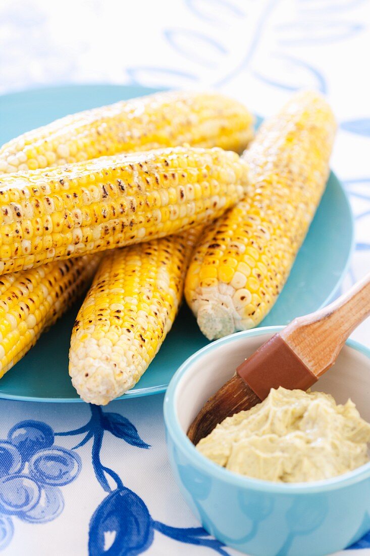 Grilled Corn on the Cob on a Blue Platter; Cutter and Basting Brush