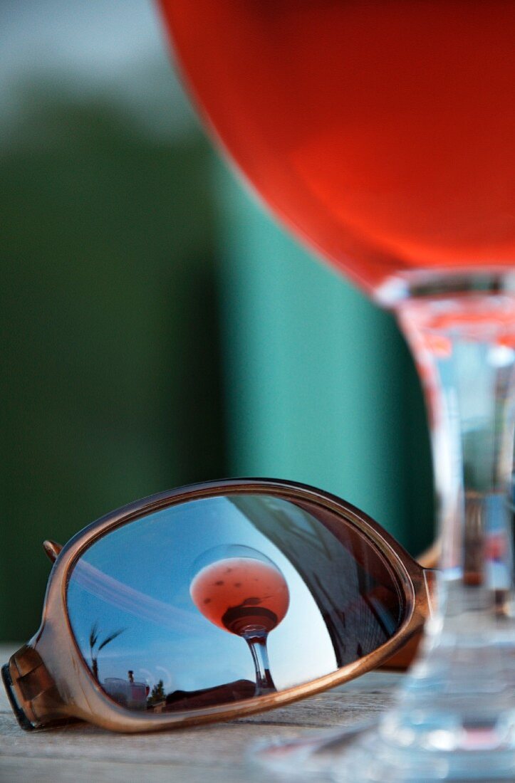 An aperitif in a glass reflected in a pair of sunglasses