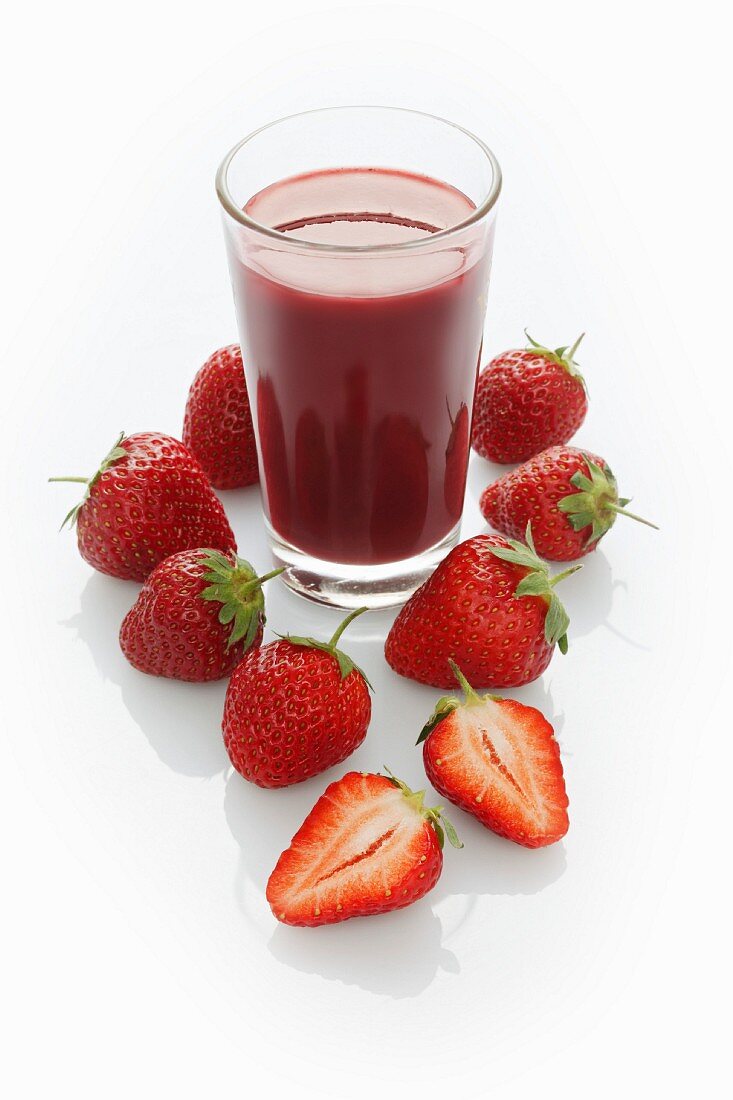 A jar of strawberry smoothie and fresh strawberries