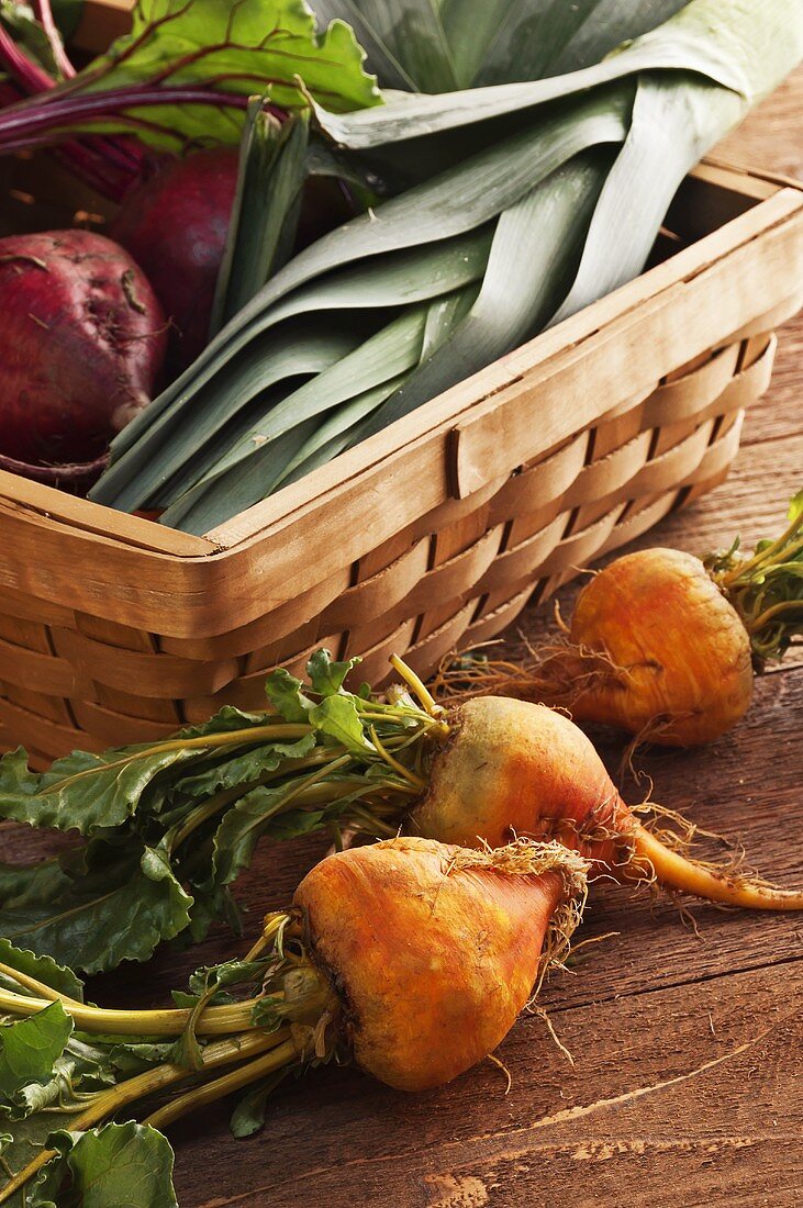 Organic Golden Beets Next to a Basket Filled with Red Beets and Leeks