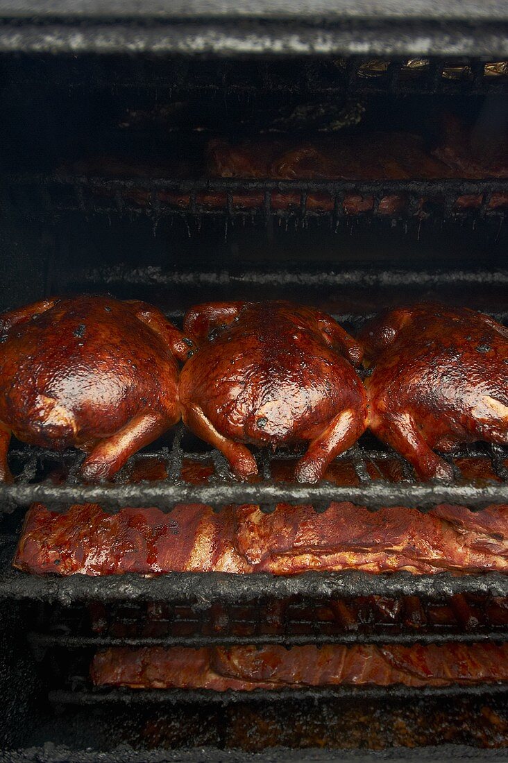 Whole Barbecue Chickens and Barbecue Ribs in a Smoker