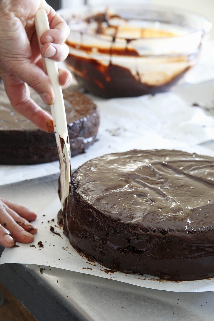 Chocolate glaze being spread onto a cake