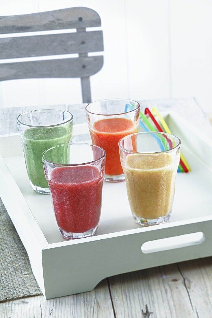 Vier Smoothies auf Tablett am Holztisch