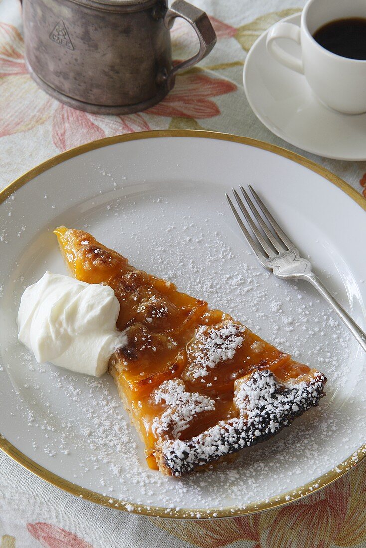 Ein Stück Pfirsichtarte mit Puderzucker und Sahne