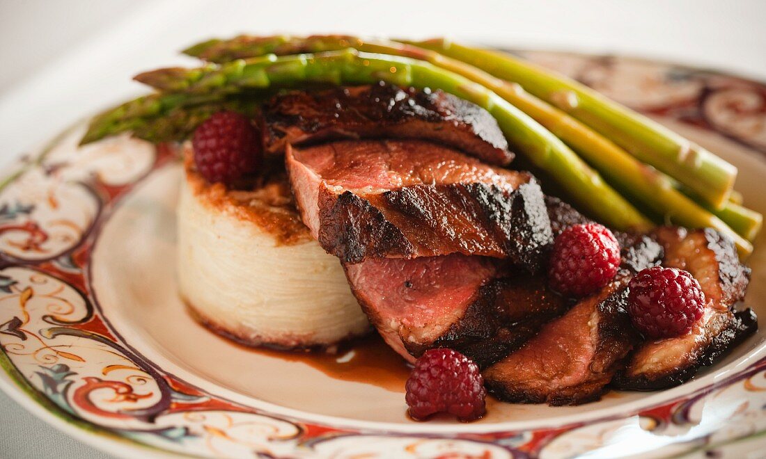 Sliced Seared Duck Breast with Potato Gratin Asparagus and Raspberries