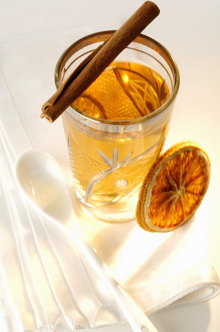 Glass of tea with cinnamon stick and slice of orange