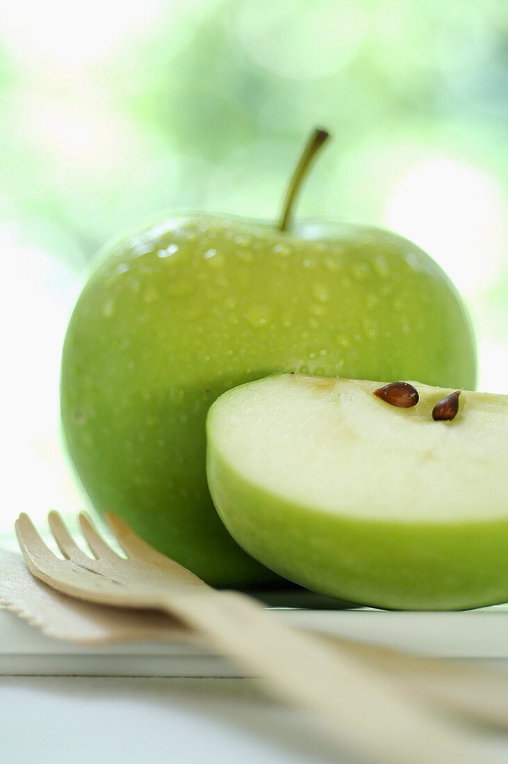 Grüner Apfel mit Wassertropfen und Apfelschnitz