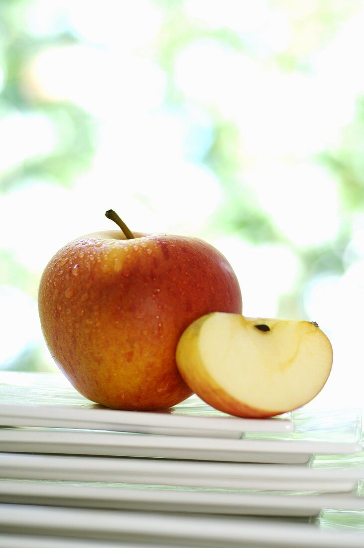 Whole apple and slice of apple on stacked plates