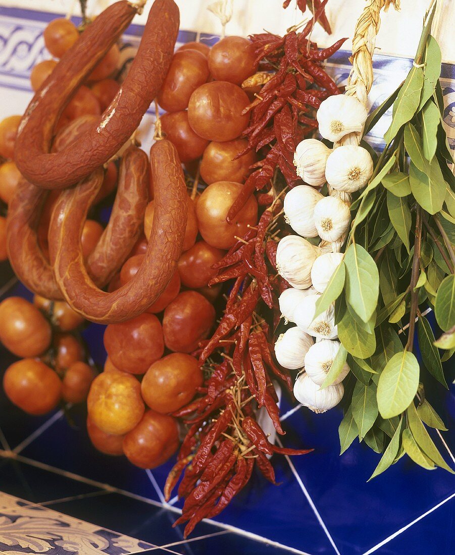 Würste, Tomaten, Chilischoten, Knoblauch, Lorbeer (hängend)