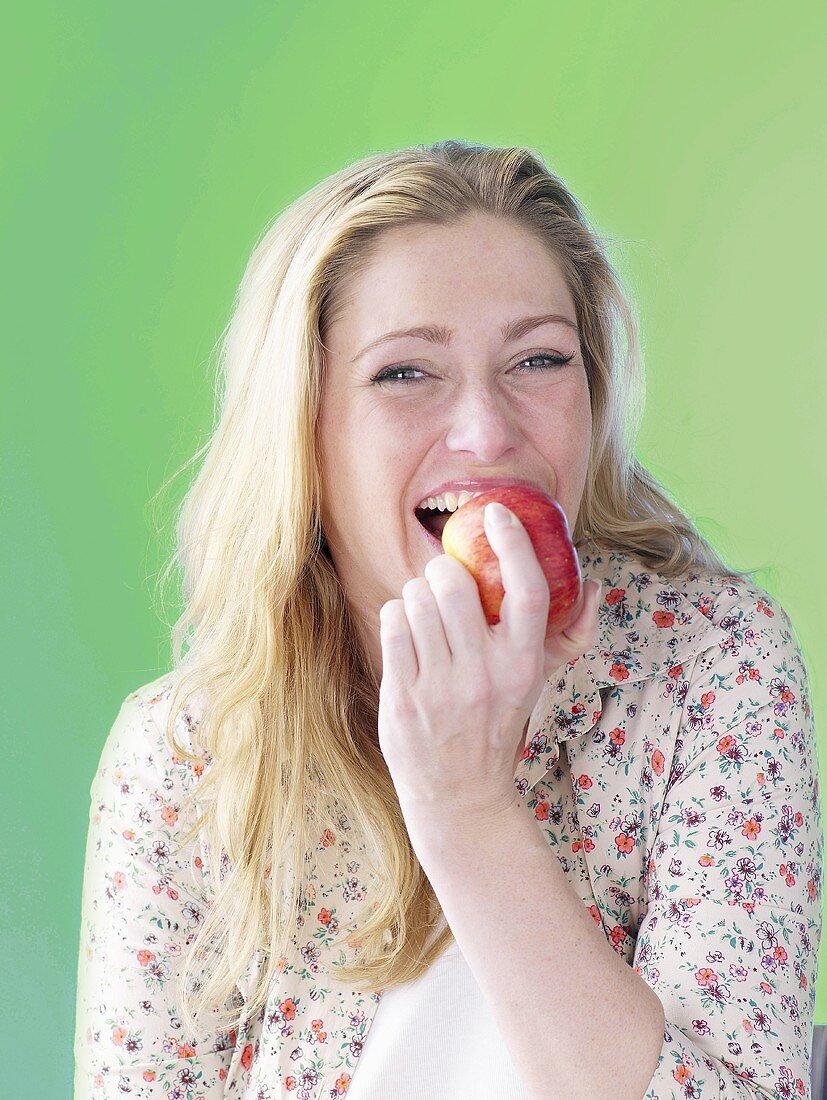 Woman biting into red apple