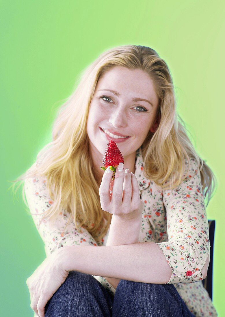 Frau hält eine Erdbeere
