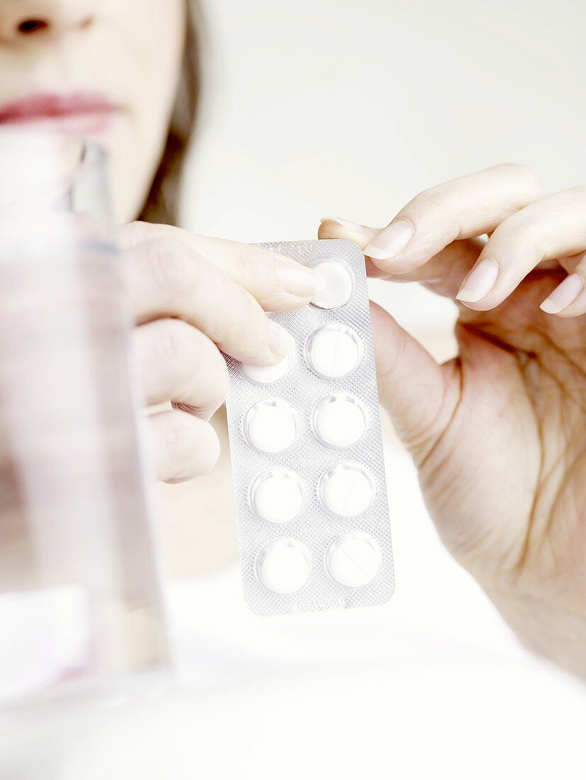 Frau nimmt Tablette aus Blisterverpackung