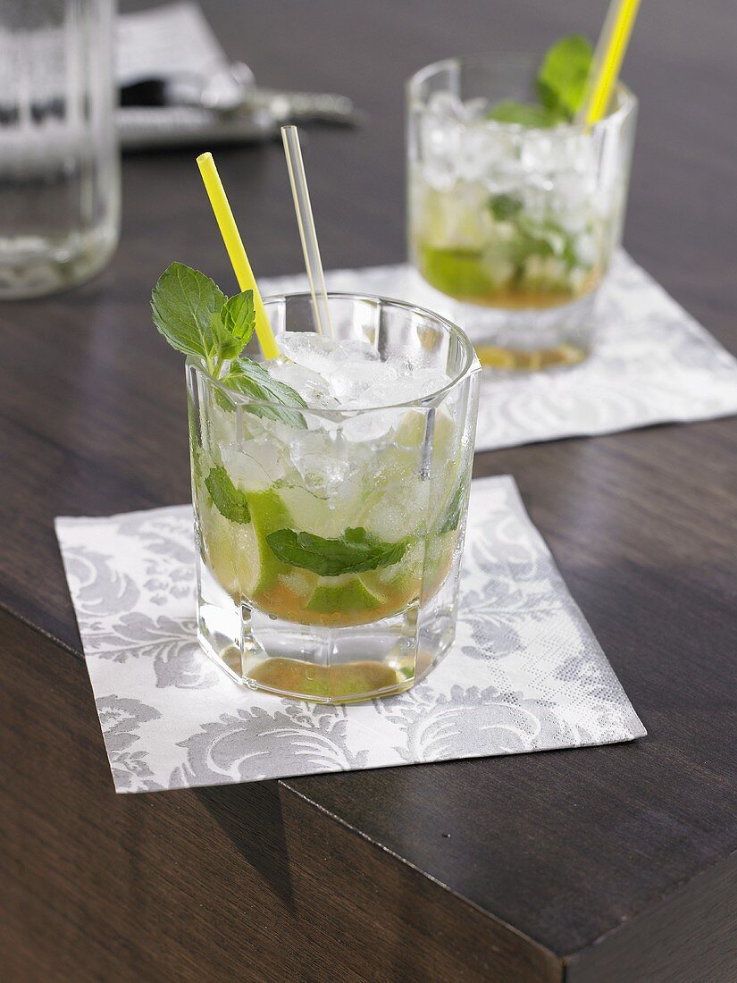 Two Mojitos on wooden table (close-up)
