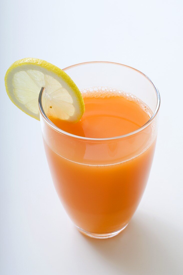 A glass of carrot juice with a slice of lemon