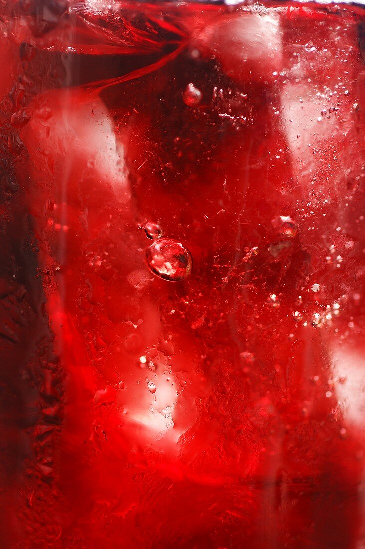 Red fruit juice with ice cubes, full-frame