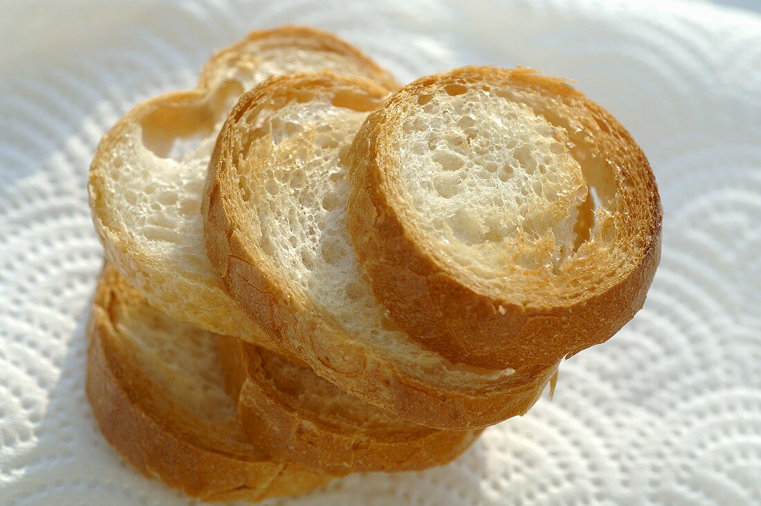 Five toasted baguette slices on kitchen paper