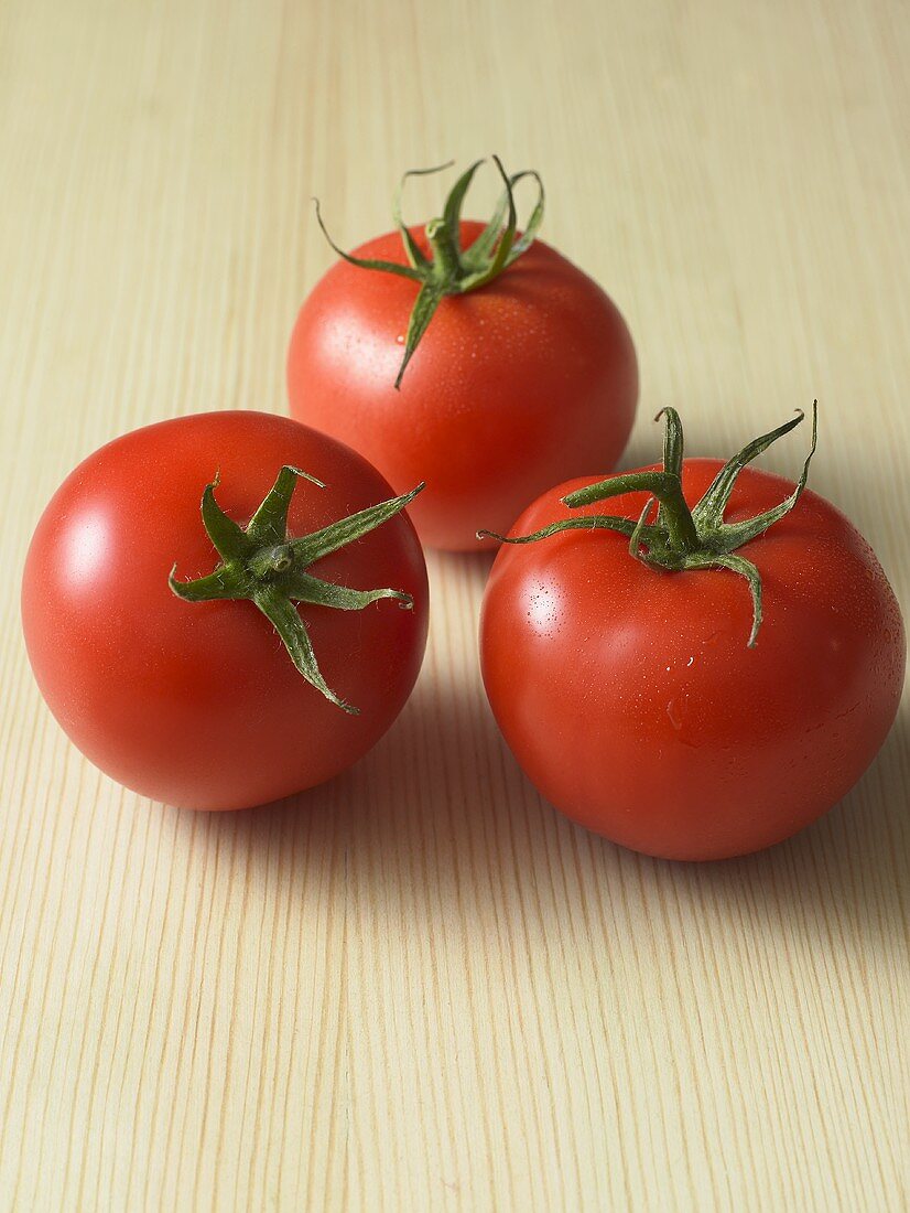 Drei frische Tomaten auf Holzuntergrund