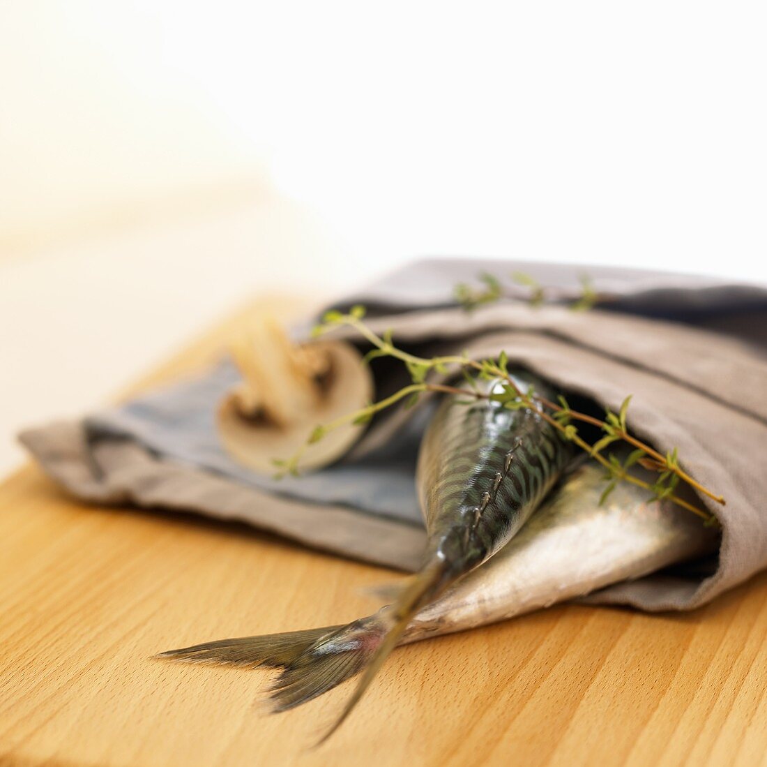 Two mackerel in a fabric napkin with mushroom and thyme