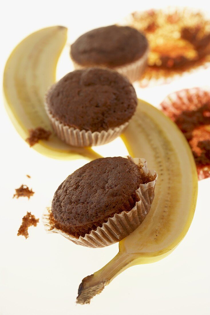 Three chocolate banana muffins with halved banana