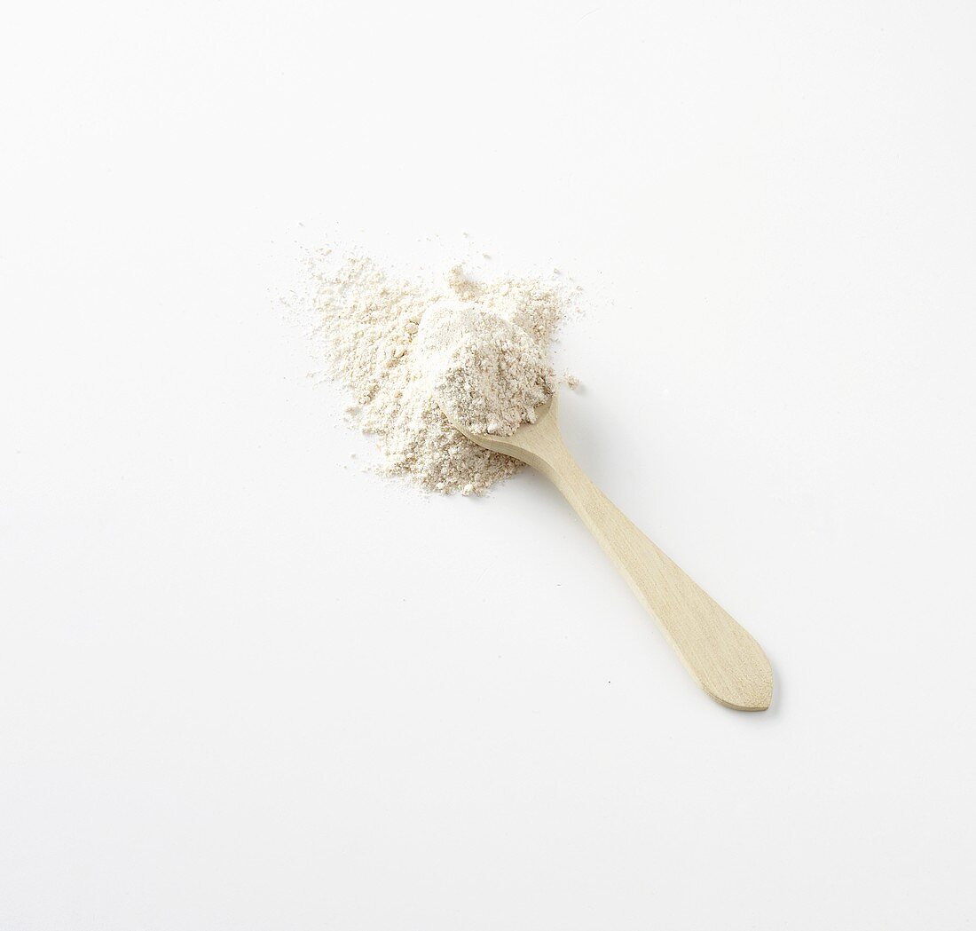Wholemeal wheat flour with a wooden spoon