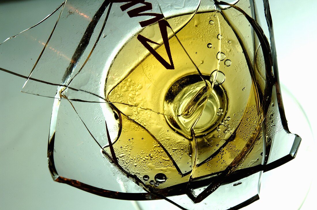 Broken wine glass with white wine