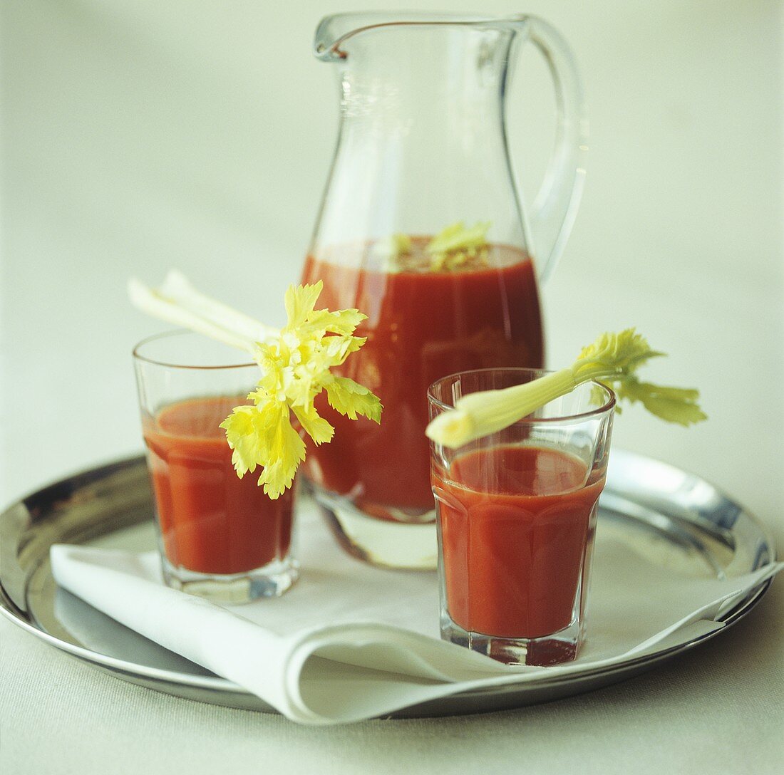 Tomatensaft mit Stangesellerie in einer Karaffe und Gläsern