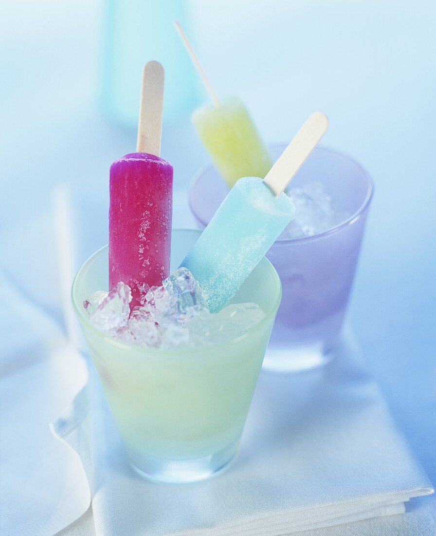 Coloured ice lollies in glasses of crushed ice