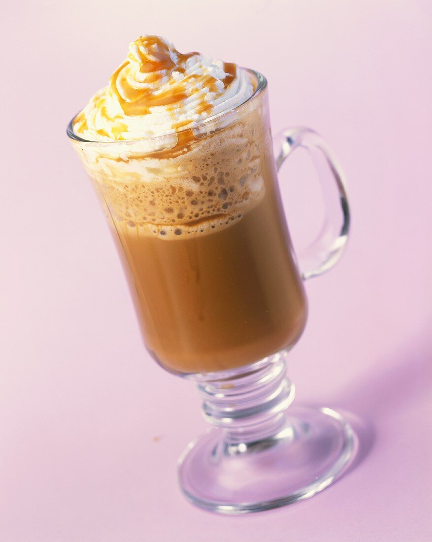 A glass of hot chocolate with whipped cream and caramel sauce