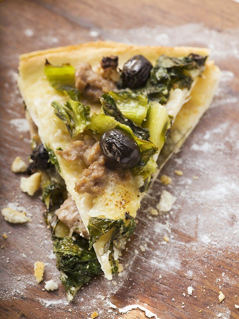 Two pieces of pizza with mince, olives, spinach and cheese