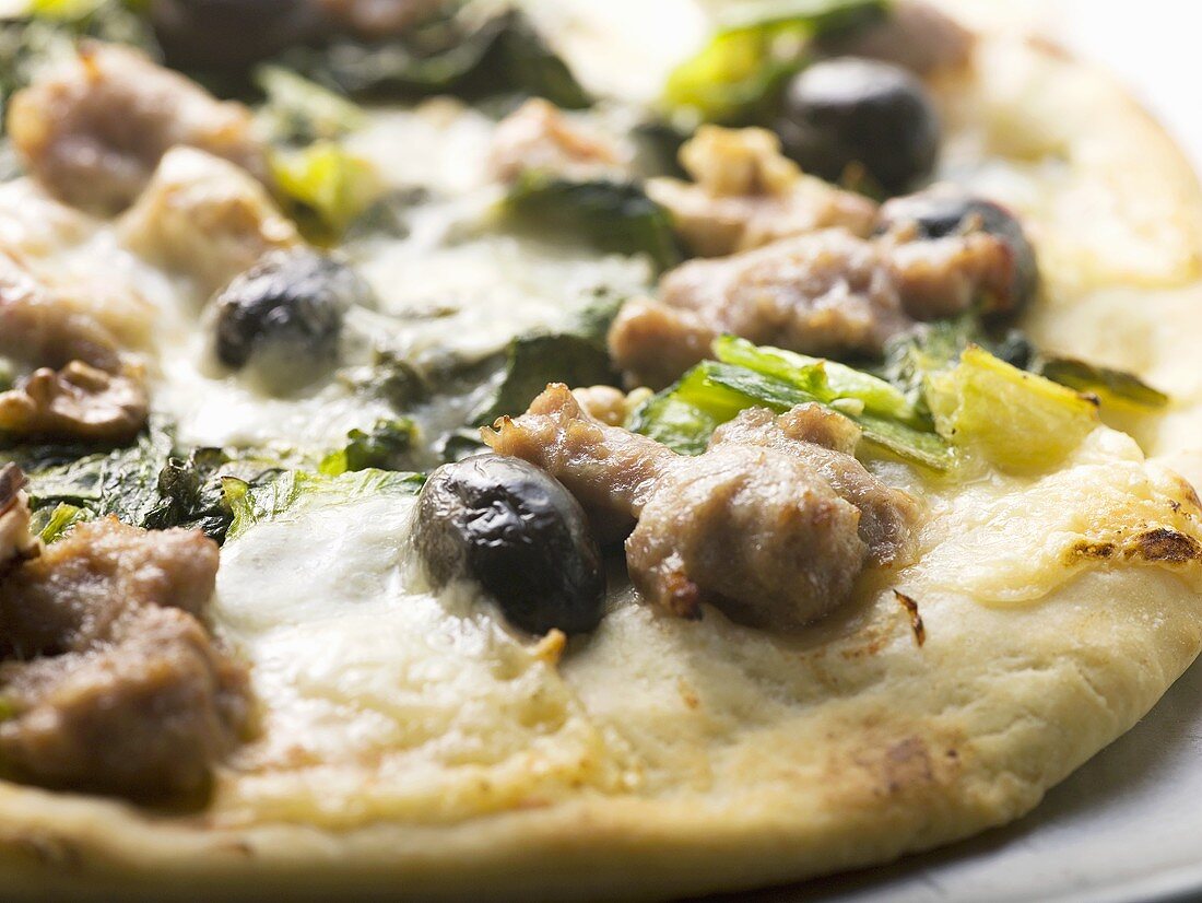 Pizza with mince, olives, spinach and cheese (close-up)