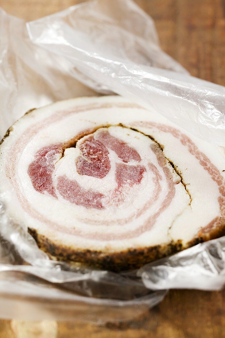 A slice of pancetta on plastic food wrap