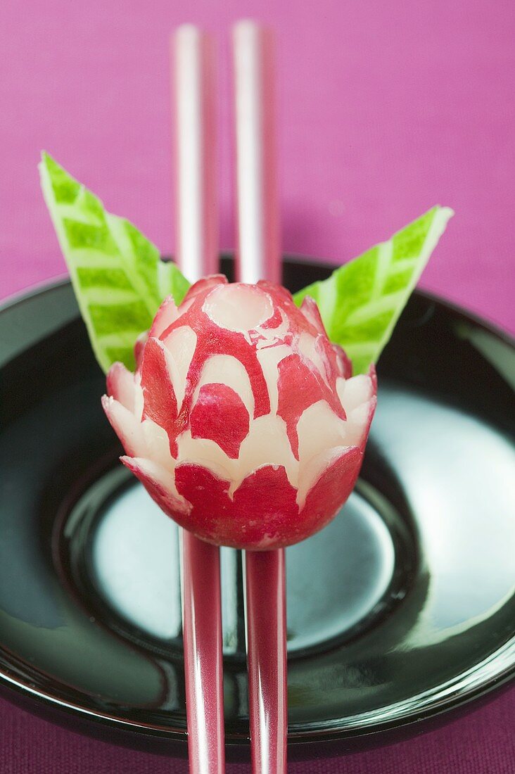 Radish flower on chopsticks, carved cucumber leaves