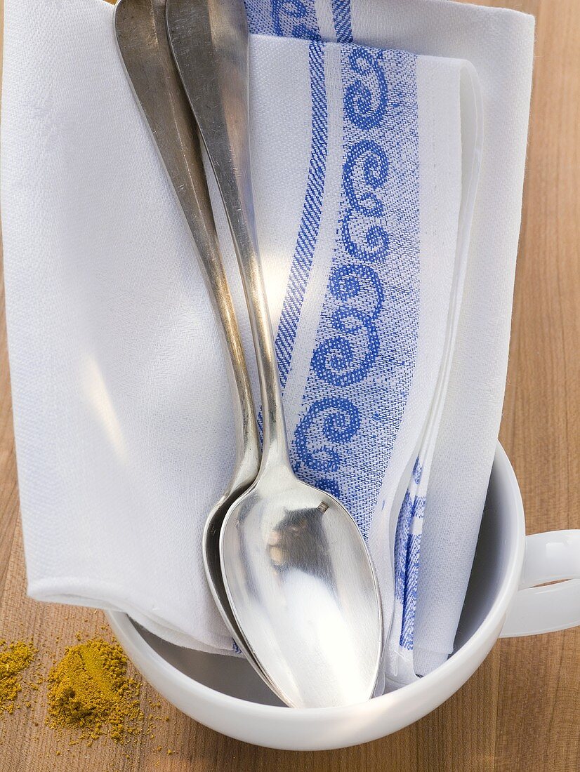 Tea towel and two spoons in white cup