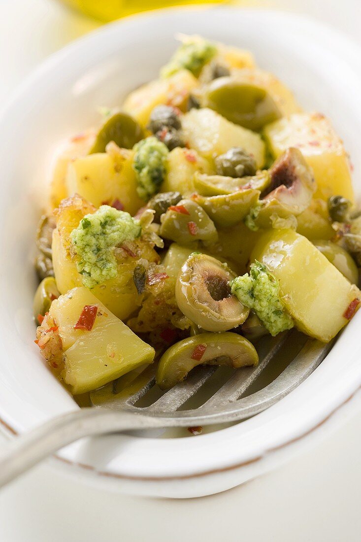 Spicy fried potatoes with olives, pesto and capers