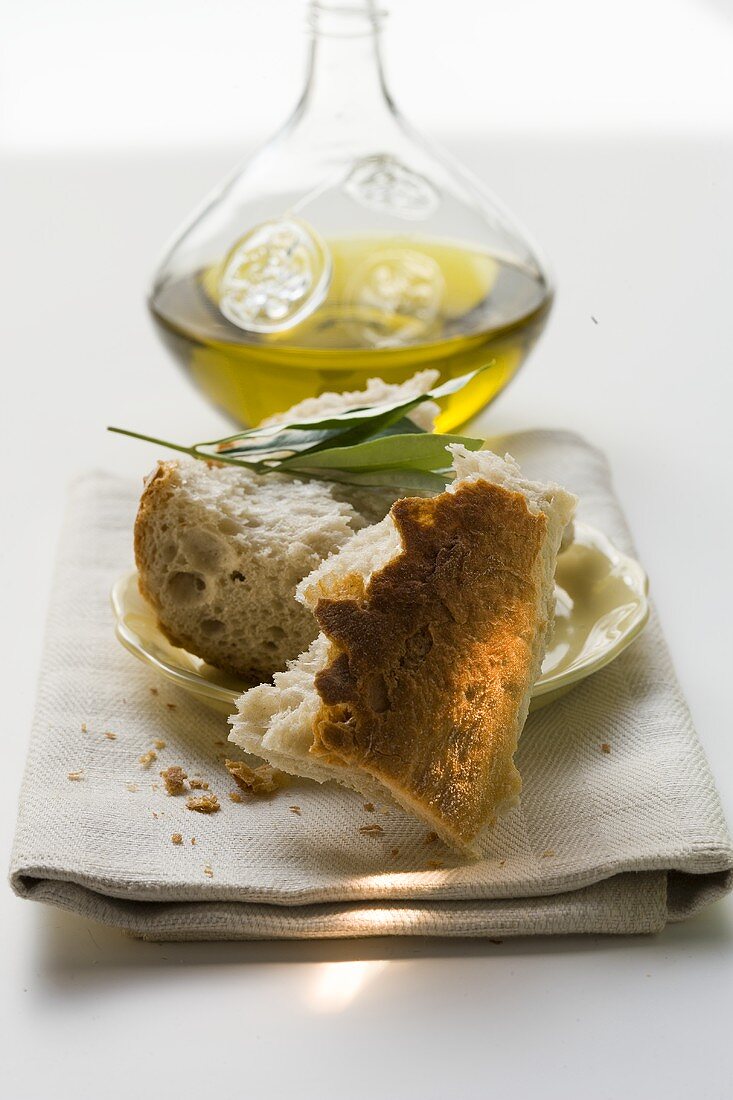 Weissbrotstücke auf Teller mit Olivenzweig, Olivenöl