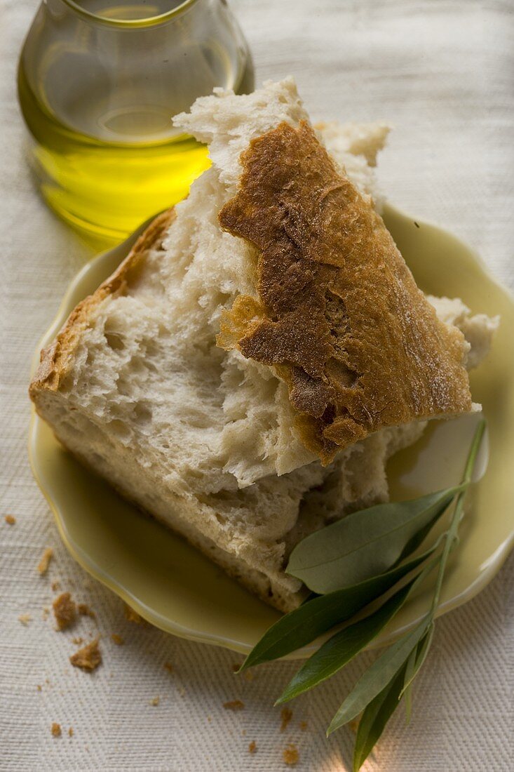 Weissbrotstücke auf Teller mit Olivenzweig, Olivenöl