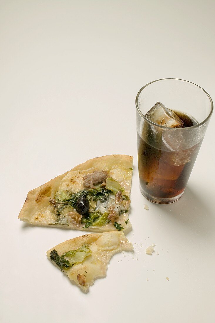 Stück Pizza mit Thunfisch, Mangold und Oliven, Glas Cola