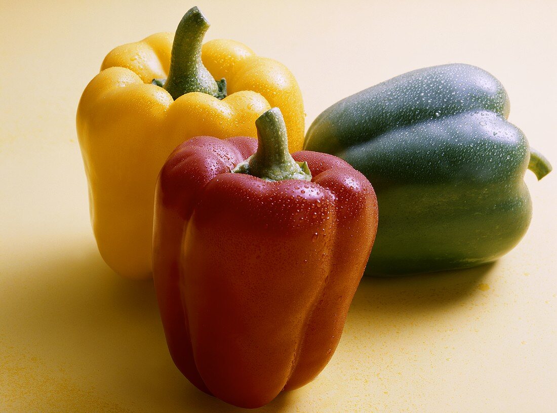 Red, yellow and green peppers with drops of water