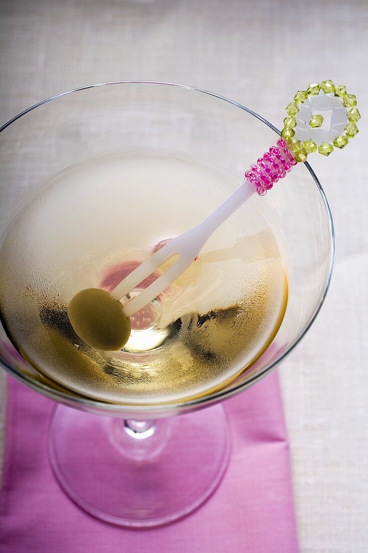 Martini mit grüner Olive auf Cocktailgabel